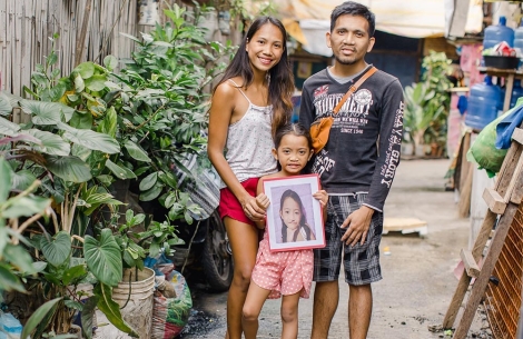 Ranelyn and Leonardo holding Leana, showing a photo of her before surgery
