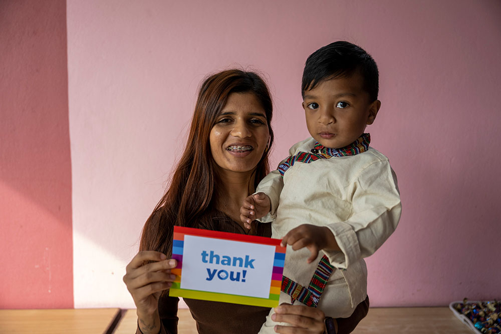 Priscilla holds up Asher, along with a card that says thank you